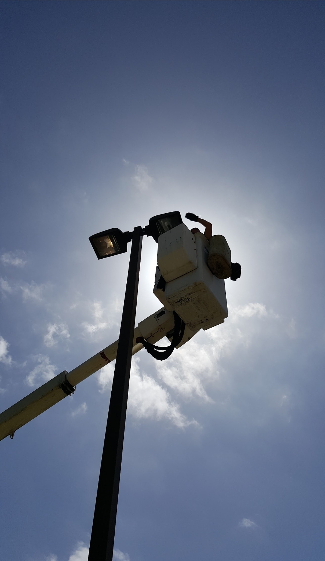 Bucket truck at parking lot pole — silhouette