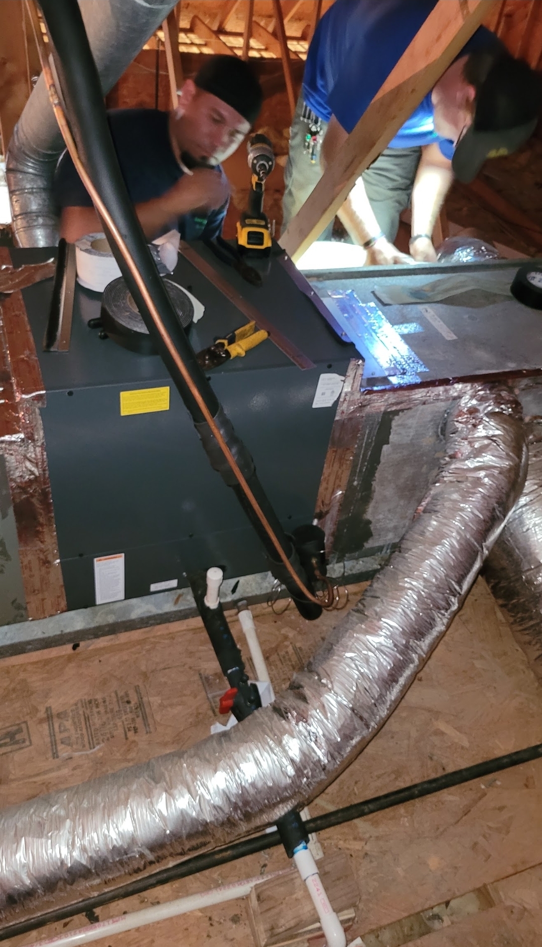 Two techs installing air handler in attic