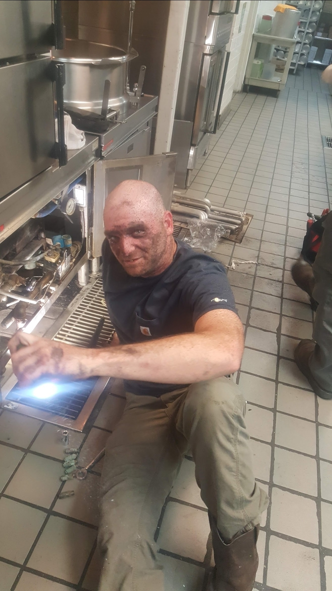 Tech covered in grease smiling after kitchen service