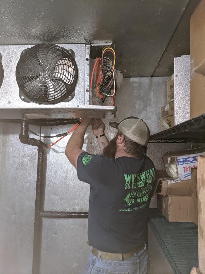 Tech inside walk-in cooler evaporator service