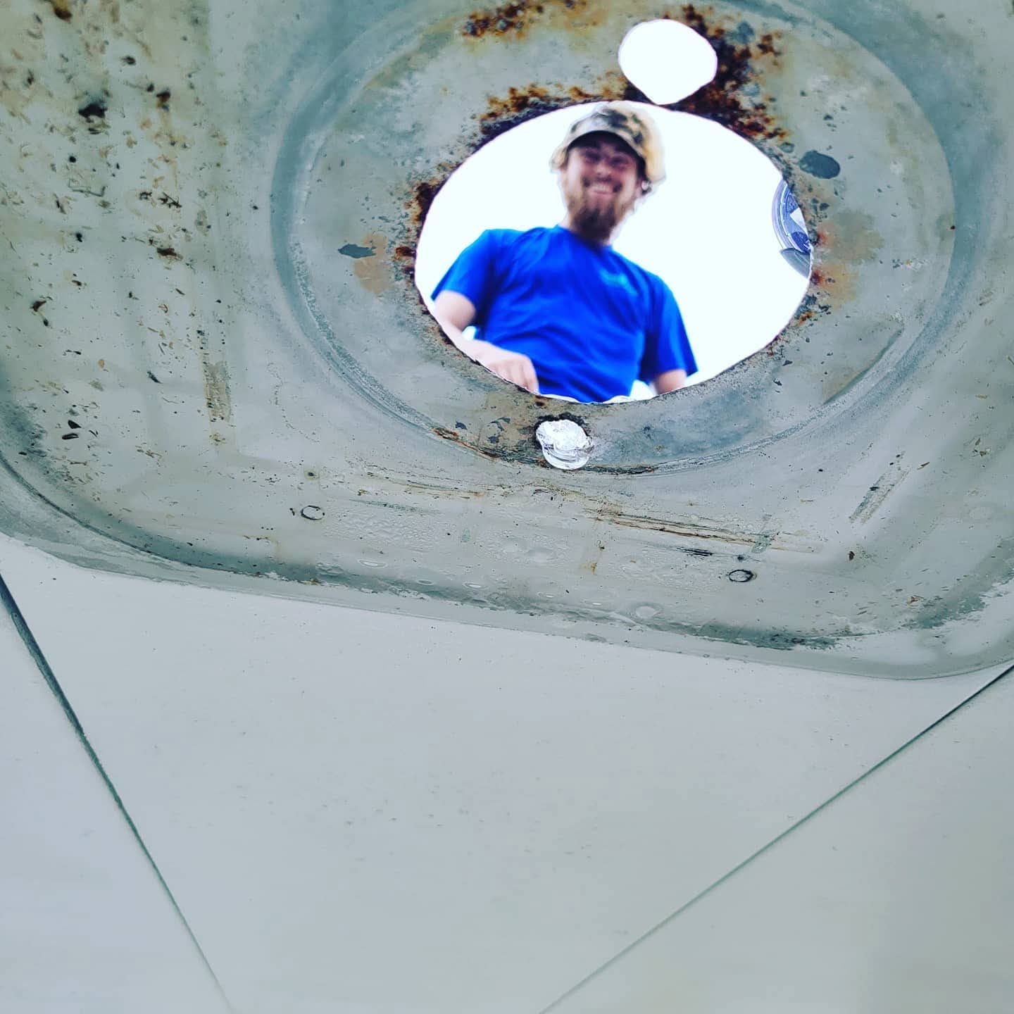 Tech smiling through rusted canopy hole